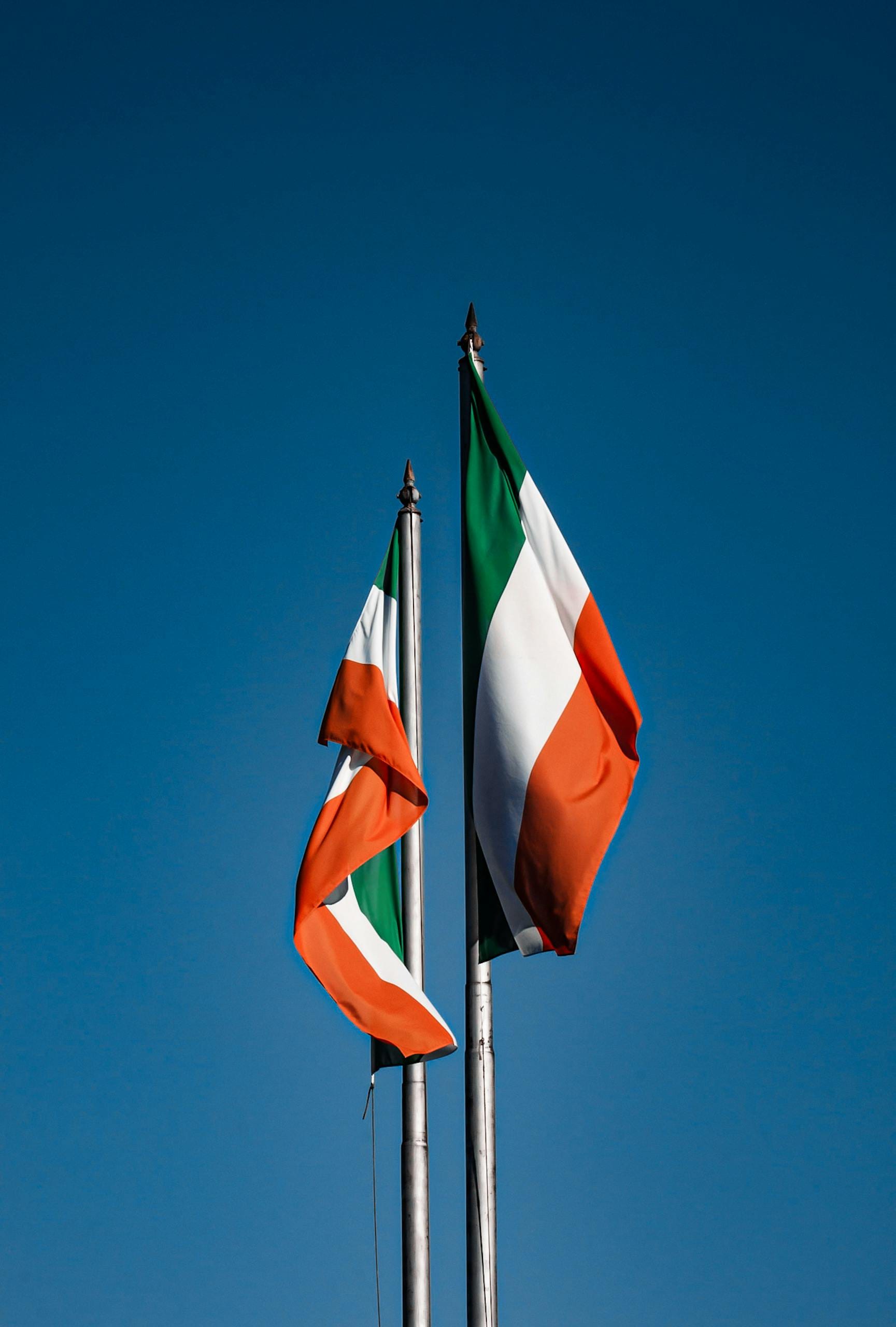 Vibrant Irish flags waving on flagpoles set against a clear blue sky in Dublin, Ireland.